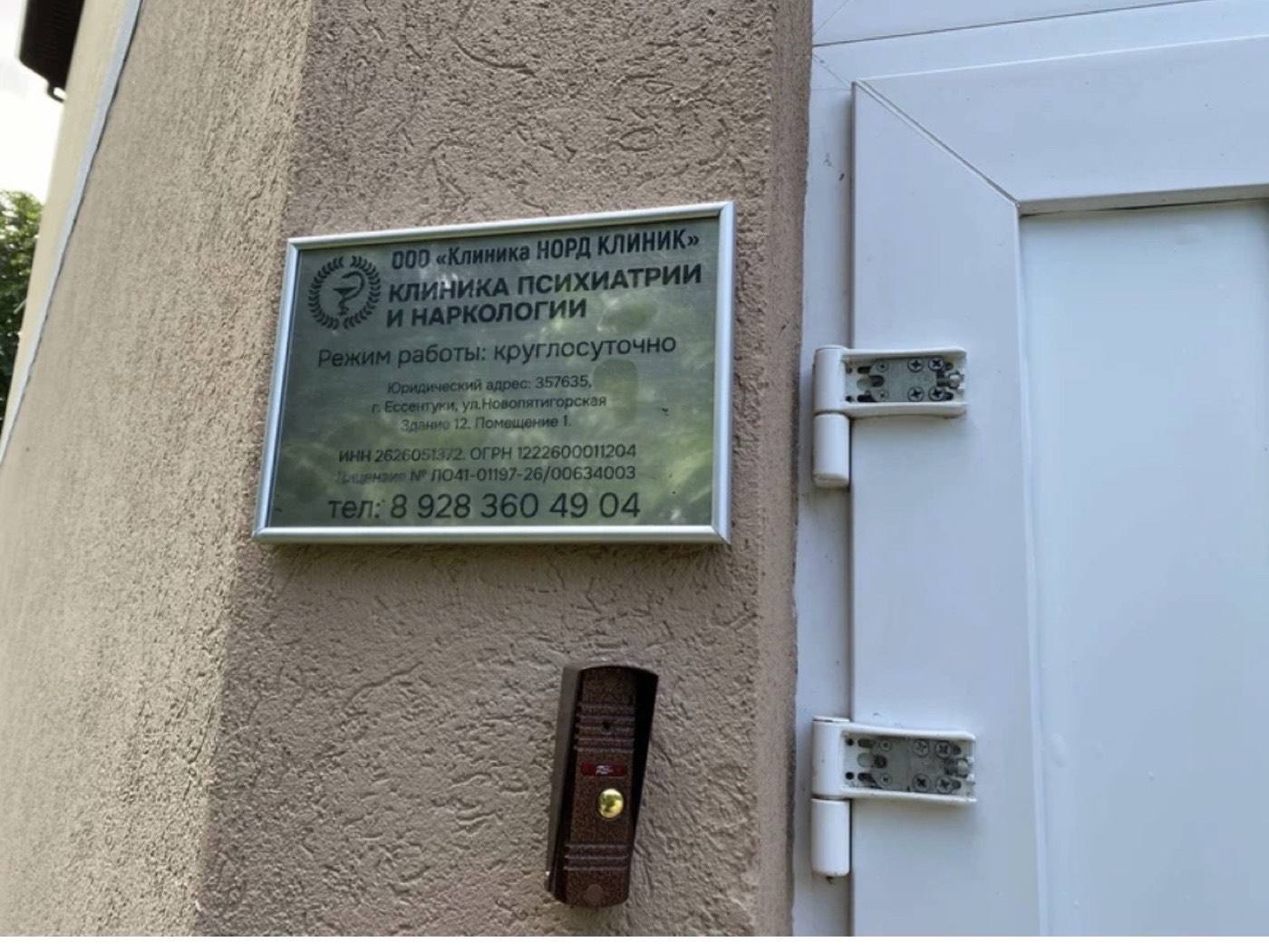 Вход в клинику Норд Клиник: белая дверь с торца здания, табличка и домофон